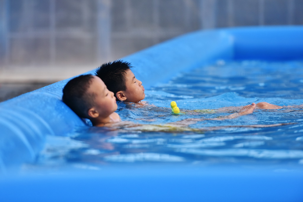 两名男孩在江西安义县水南村的一处嬉水区休息（8月8日摄）。
