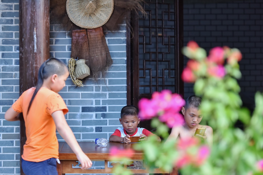 三名男孩在江西南昌安义县水南赣派小吃街上休闲纳凉（8月8日摄）。