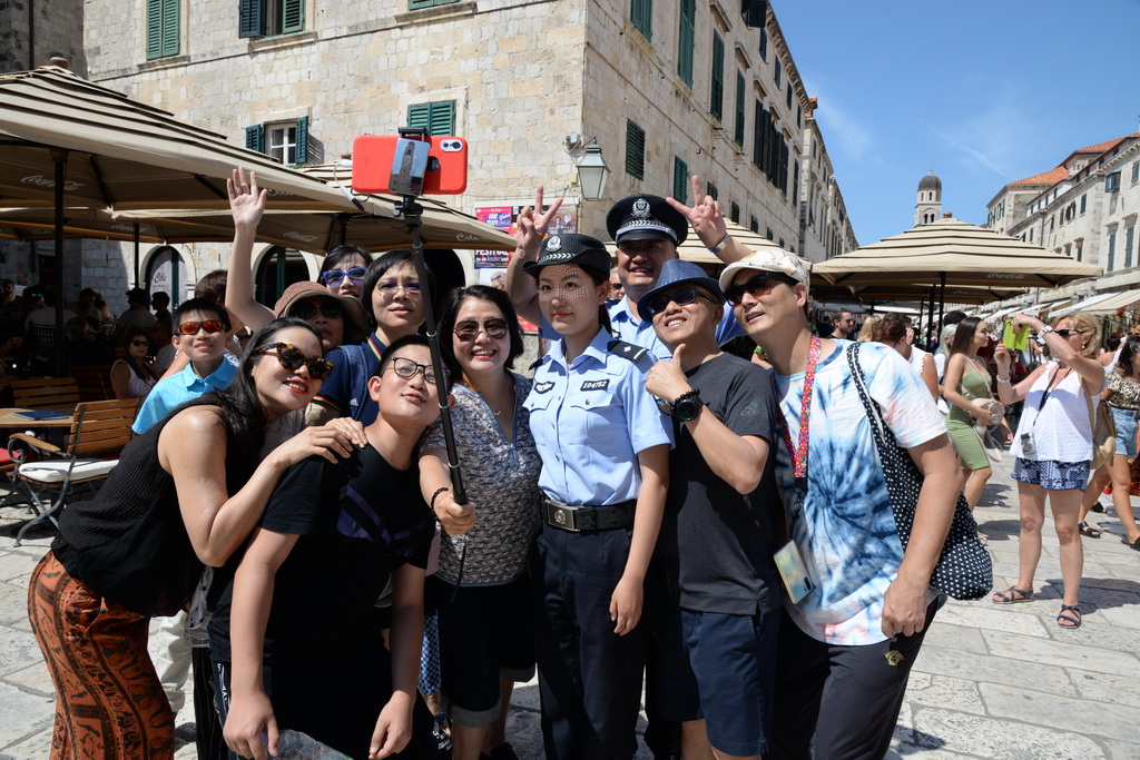 這是8月9日，參加中國與克羅地亞第二次旅游季警務聯合巡邏的警官在克羅地亞南部城市杜布羅夫尼克與游客合影。