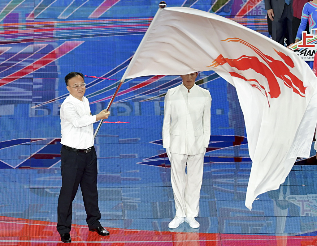 8月18日，廣西壯族自治區副主席黃俊華（左）代表第三屆全國青年運動會承辦方接過青運會會旗后揮舞旗幟。新華社記者曹陽攝