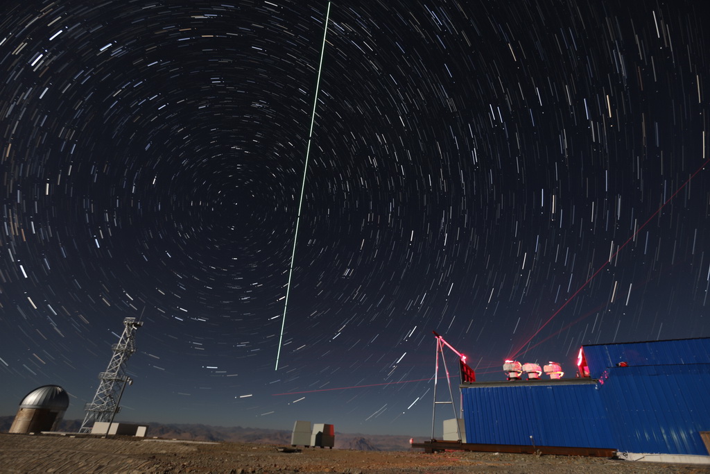 在西藏阿裡觀測站，“墨子號”量子科學實驗衛星過境，科研人員在做實驗（2016年12月10日攝，合成照片）。新華社記者 金立旺 攝
