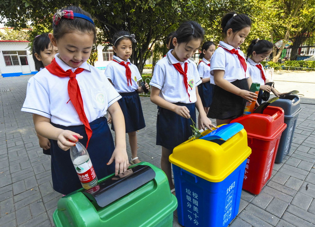 9月3日，河北省文安縣第二小學學生將不同種類垃圾投入垃圾桶中。