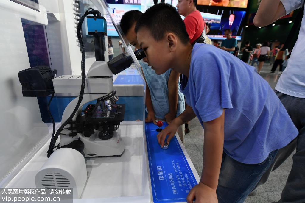9月14日，小朋友正在通過顯微鏡觀察中國芯。