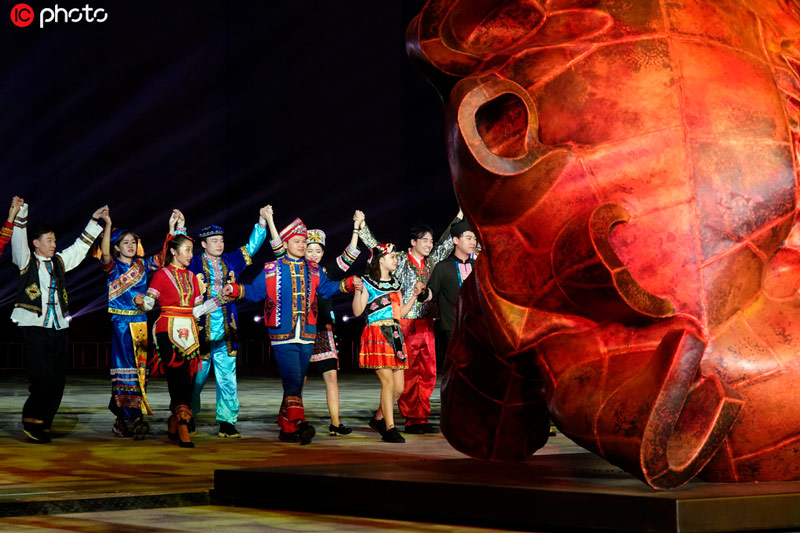 身穿我國56個民族服飾的演員在大型葵園雕塑間歡舞。