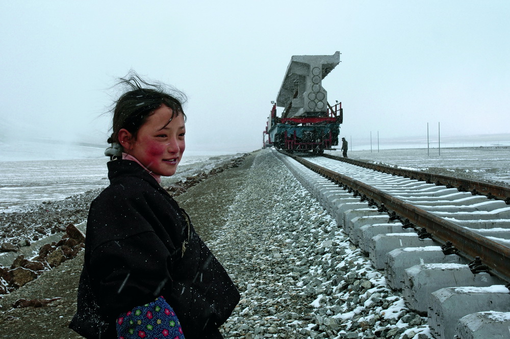 2005年3月12日，西藏自治區北部那曲縣，牧民們帶著兒女從幾十裡外步行來到正在鋪軌架橋的青藏鐵路施工現場，這是他們有生以來第一次見到鐵路和火車。青藏鐵路2006年全線通車，是從青海省西寧市至西藏自治區拉薩市的國鐵Ⅰ級鐵路，是中國新世紀四大工程之一，是通往西藏腹地的第一條鐵路，也是世界上海拔最高、線路最長的高原鐵路。王守明 攝