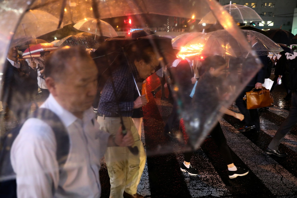 10月11日，在日本东京，人们在雨中撑伞过马路。新华社/路透
