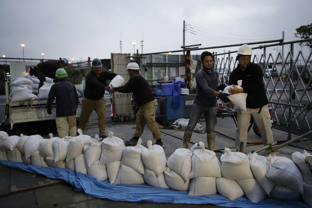 10月11日，在日本神奈川县的江之岛，人们传递防洪沙袋。新华社/美联