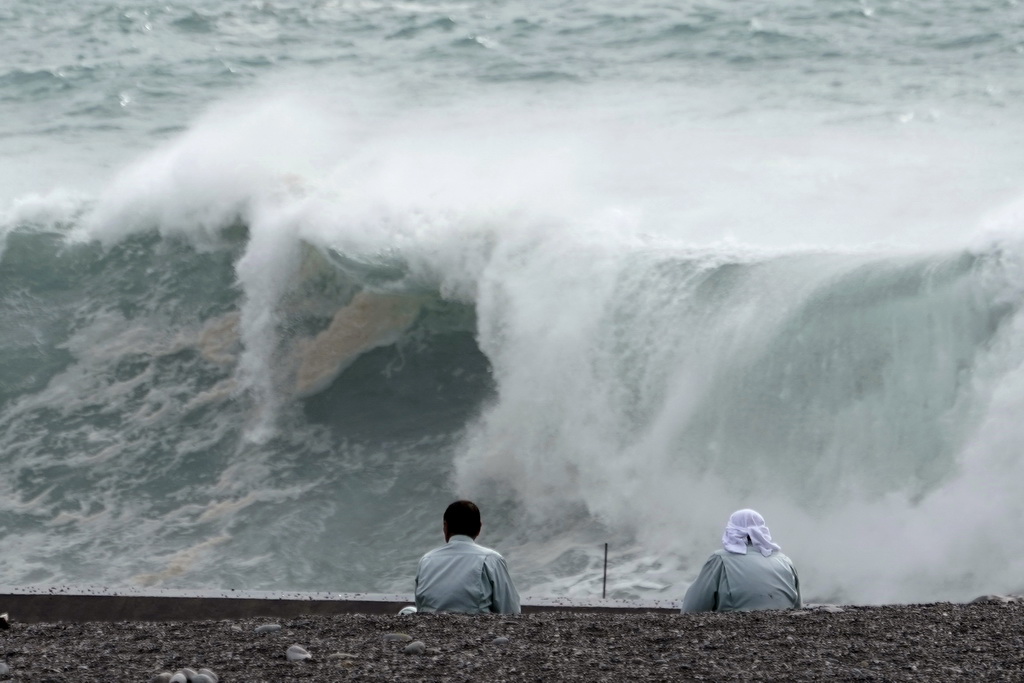 10月11日，在日本三重县，两名男子观望海浪。新华社/美联