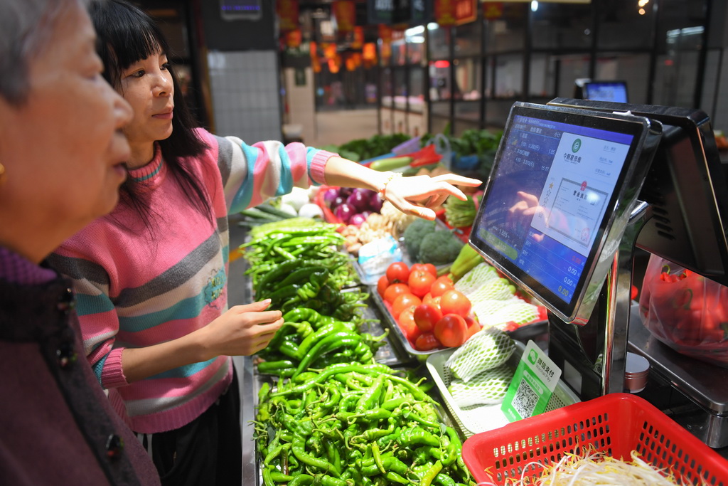10月15日，今朝星市集智慧農貿市場的經營戶在幫助市民查看菜品信息。