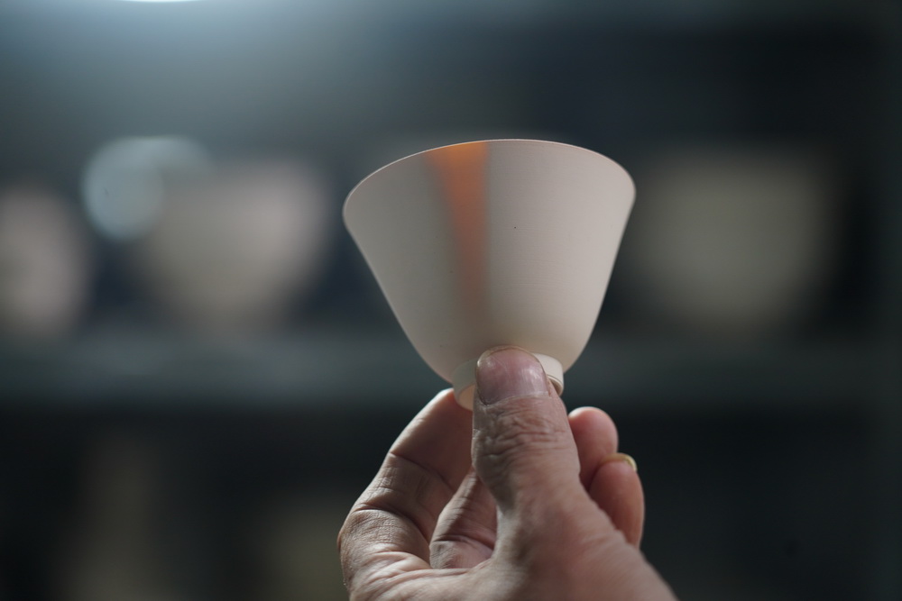 這是一隻利坯后的薄胎瓷杯，滴上一滴水后，杯壁在燈光下顯出蛋殼一樣的通透效果，這是手工薄胎匠人檢驗成品厚度的傳統辦法（10月28日攝）。