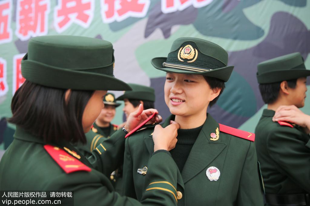 12月12日，武警重慶總隊新兵團女兵班班長正在給一名女兵佩戴肩章。