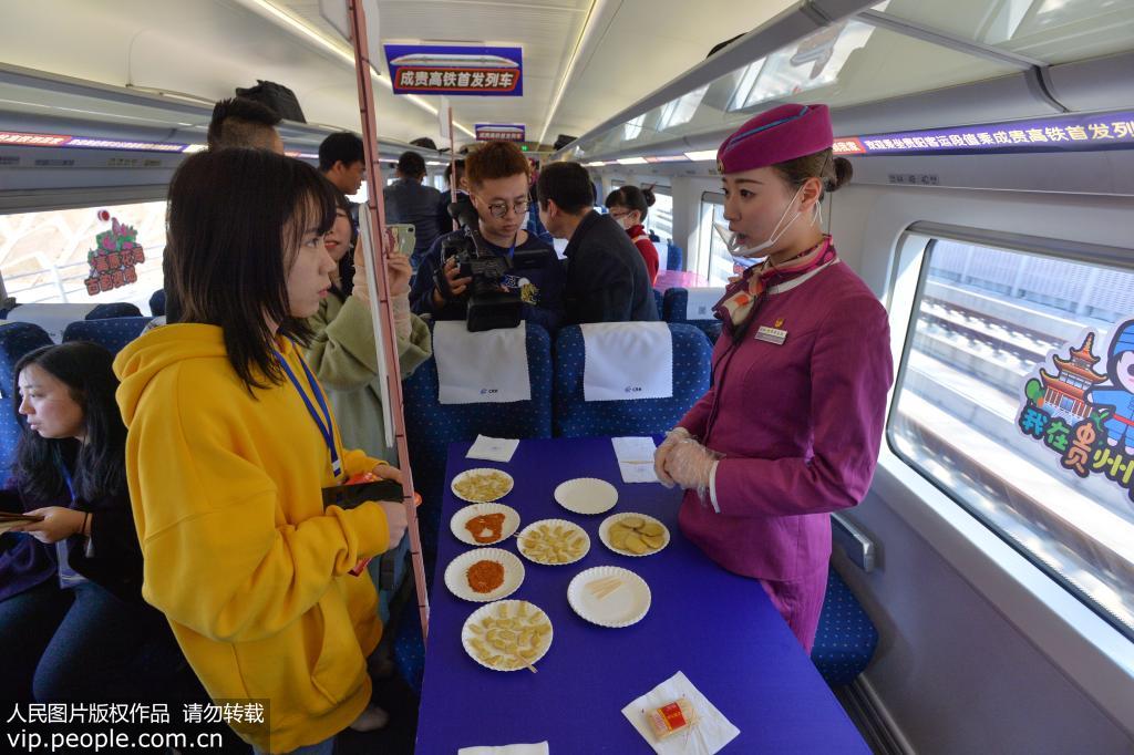12月16日，動車乘務員在開往成都南的C6008次動車上為旅客介紹貴州特色小吃豆腐干。喬啟明/人民圖片