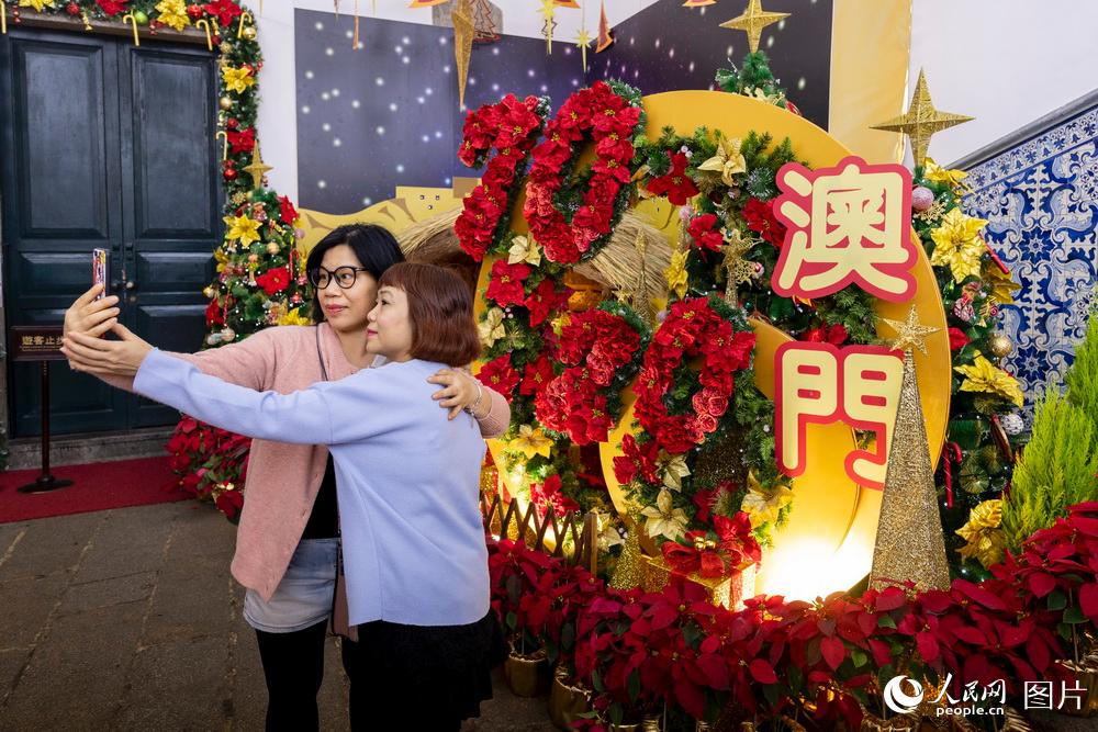 12月18日，民眾在慶祝回歸花壇前拍照留影。