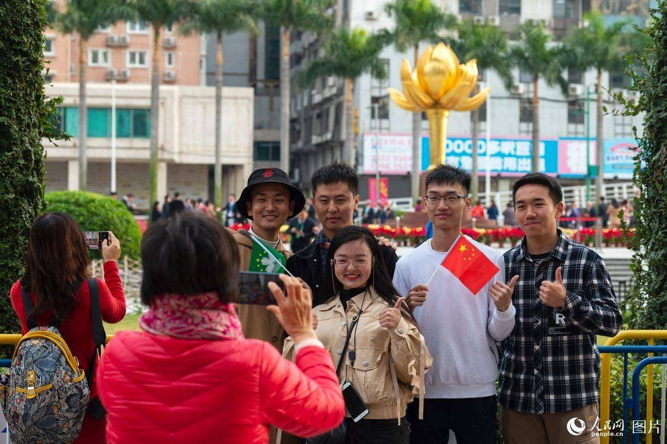 12月20日，在金蓮花廣場，游人手舉國旗區旗拍照留影。