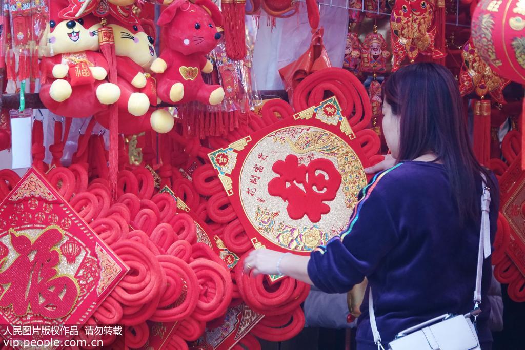 1月2日，一名市民在南寧市上海路的年貨集市選購福字挂飾。