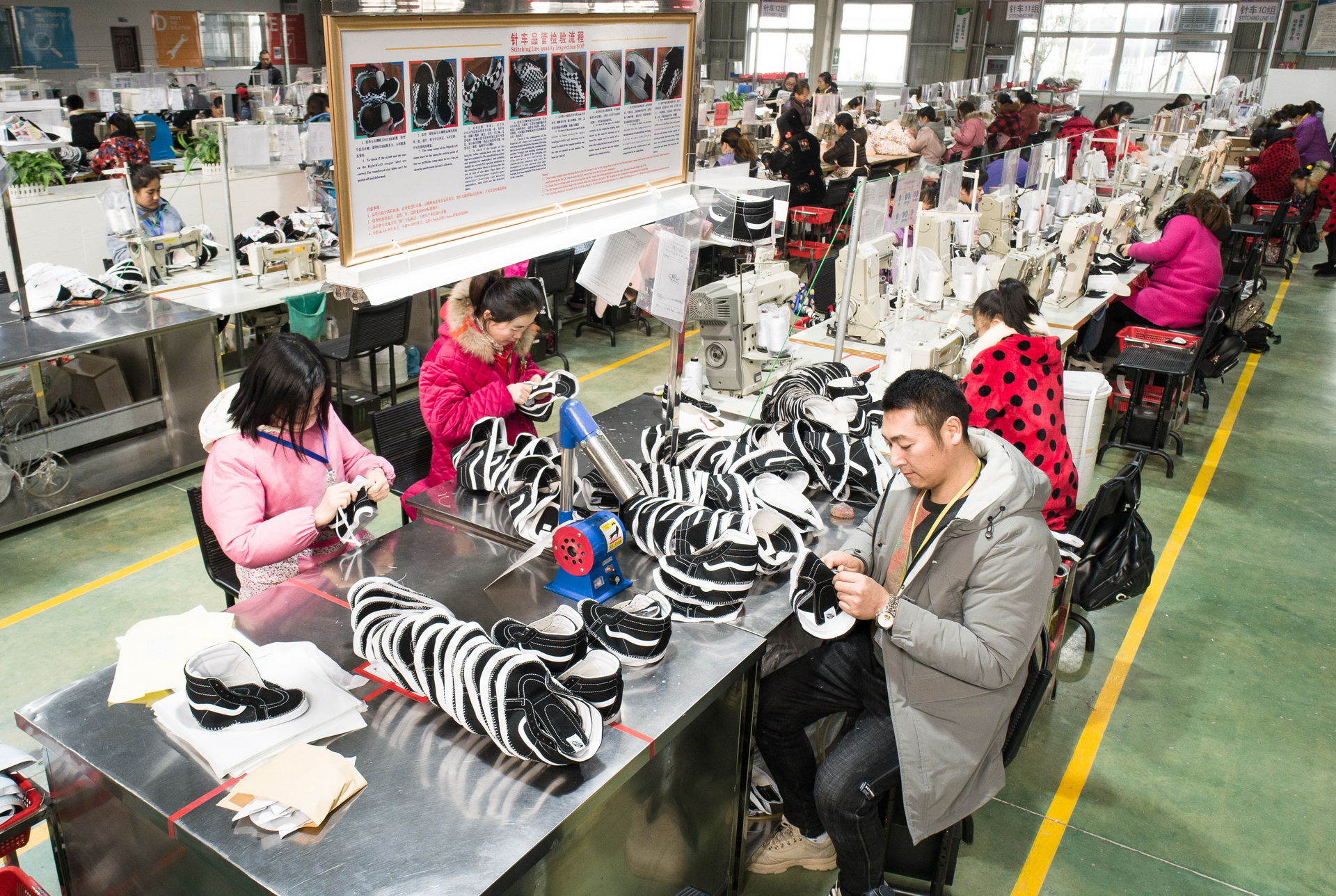 “上岸”后的徐保安（前右）在一家鞋業公司加工車間內工作（2019年12月26日攝）。