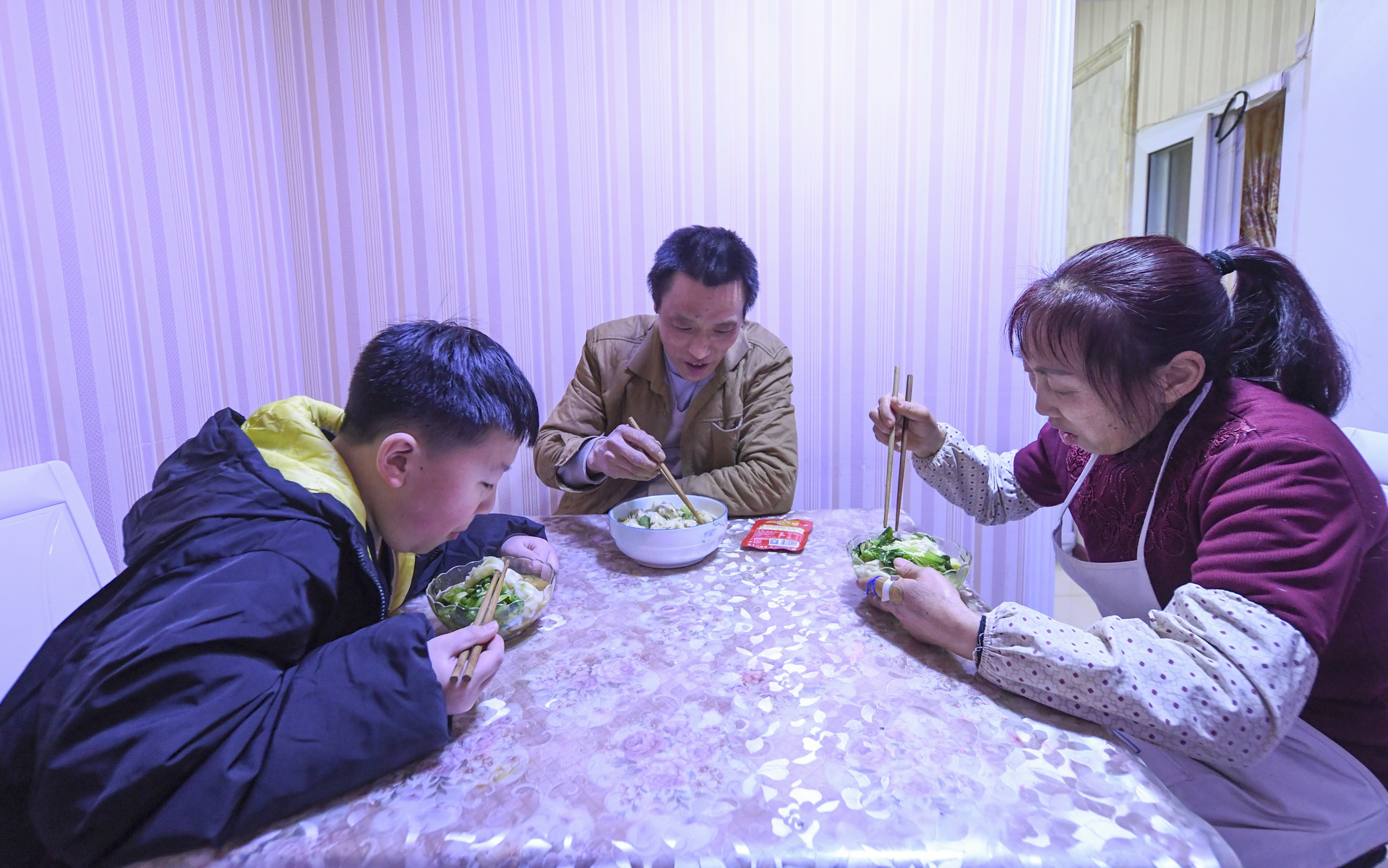冉光輝和妻子瞿光芳、兒子冉俊超在家裡吃晚飯（1月5日攝）。