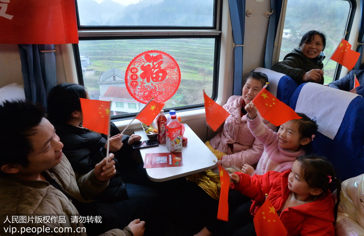 1月14日，外出務工人員和小孩在上海南-貴陽K111次列車車廂內揮舞五星紅旗歡慶新年。