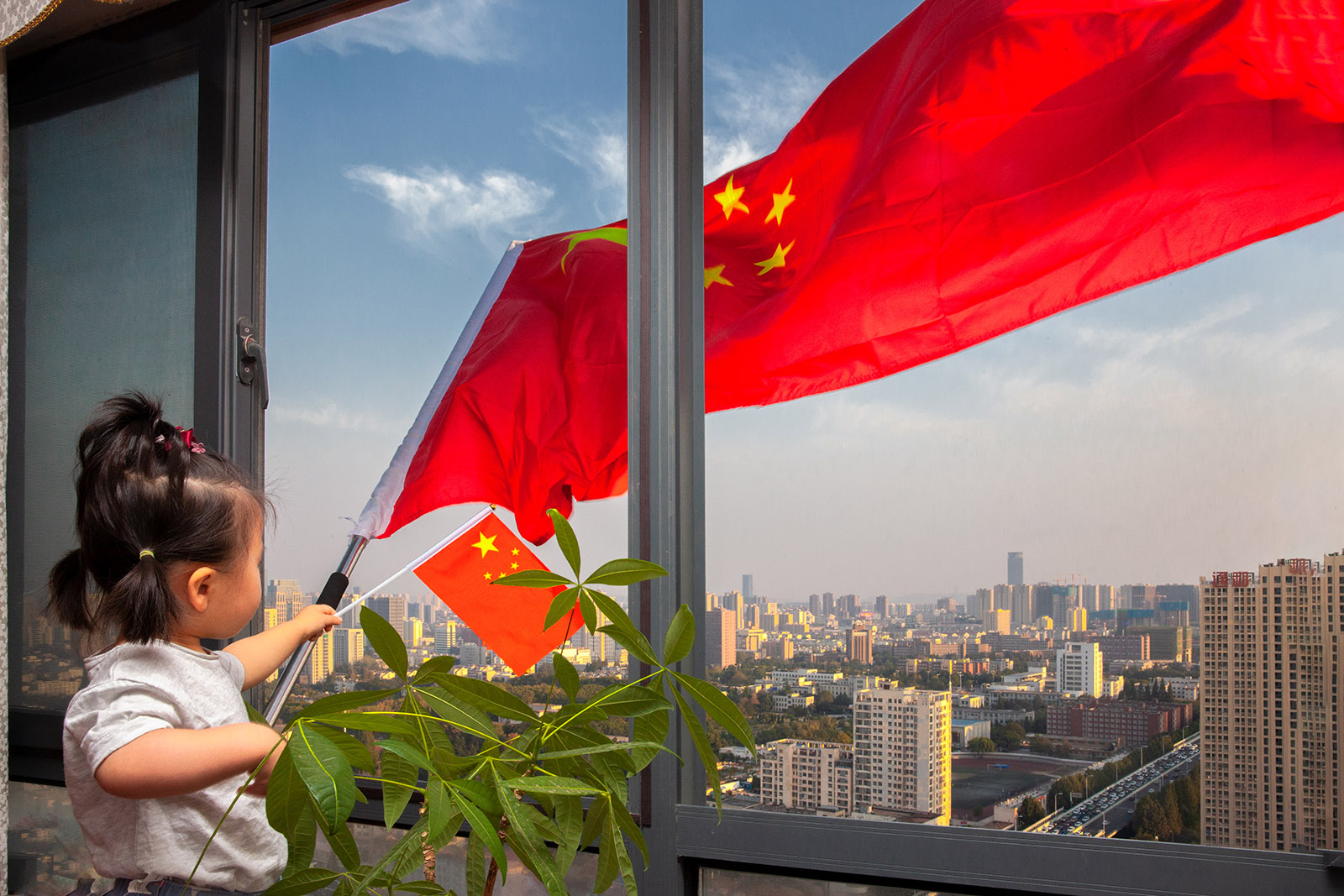 龔思諾(小學組)北京《五星紅旗》 國慶70周年前夕，妹妹拿著國旗站在陽台上，五星紅旗迎風飄揚。搜索復制
