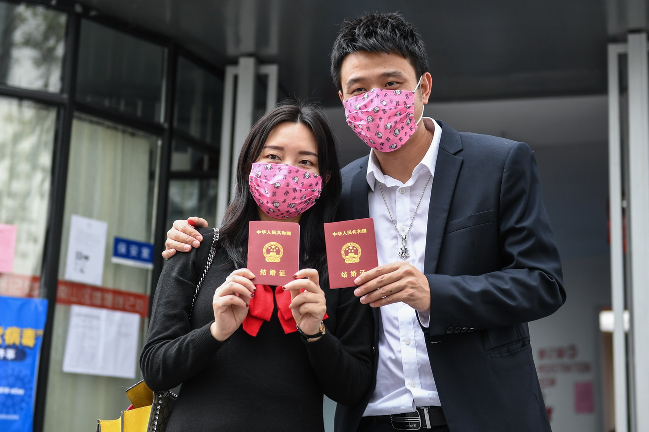 2月14日，在深圳市南山區民政局婚姻登記處前，完成結婚登記的鄧玲玲（左）和鄧俊威戴著口罩展示結婚証。