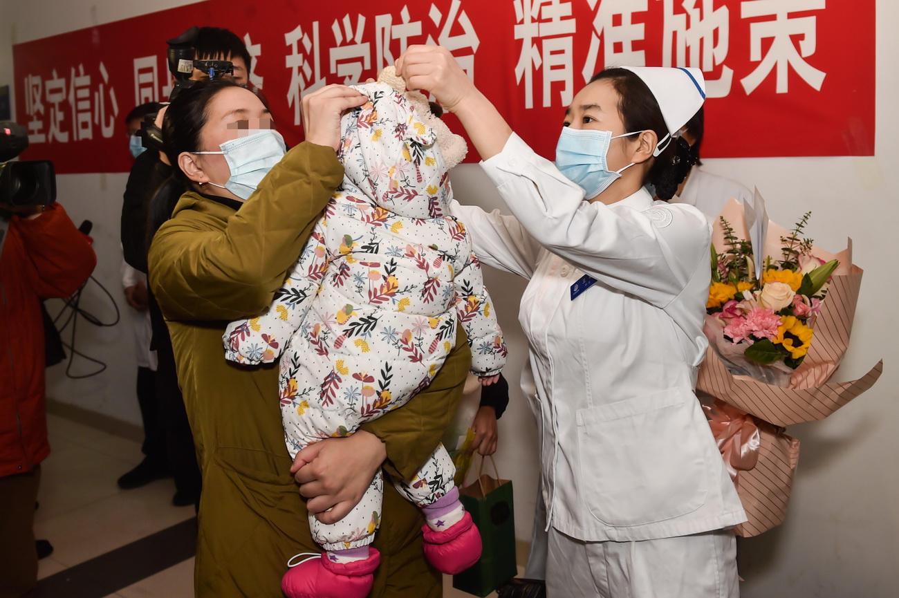2月14日，护士长王颖（右）在出门前帮奇奇（化名）戴好帽子。新华社发（彭子洋 摄）