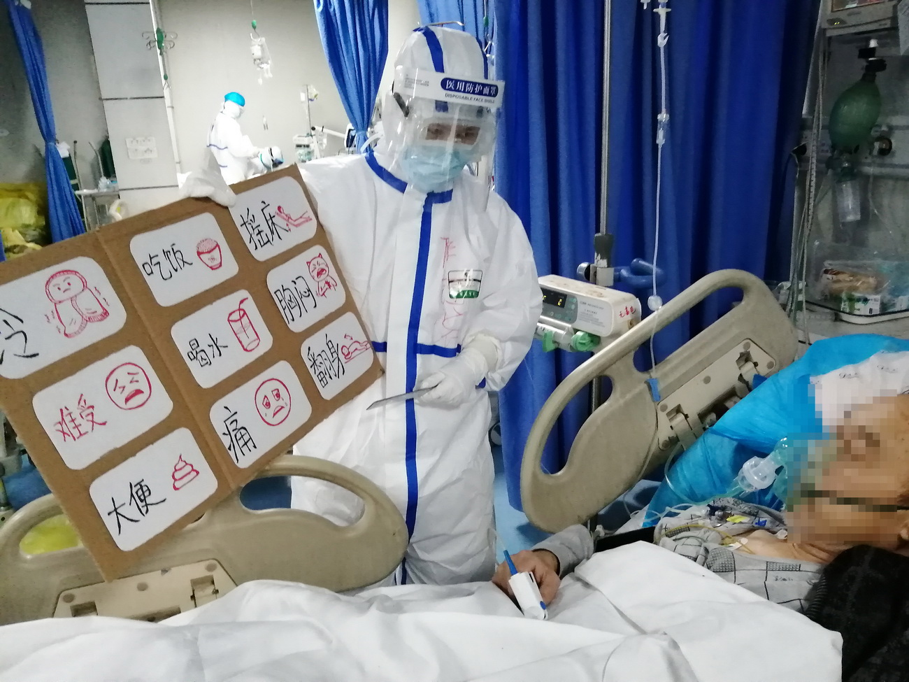 在武漢市第五醫院重症病區，來自江西省人民醫院第一批援助武漢的護士陳鈺浠給患者看她的“圖解護理需求表”，以方便雙方的交流（2月24日攝）。