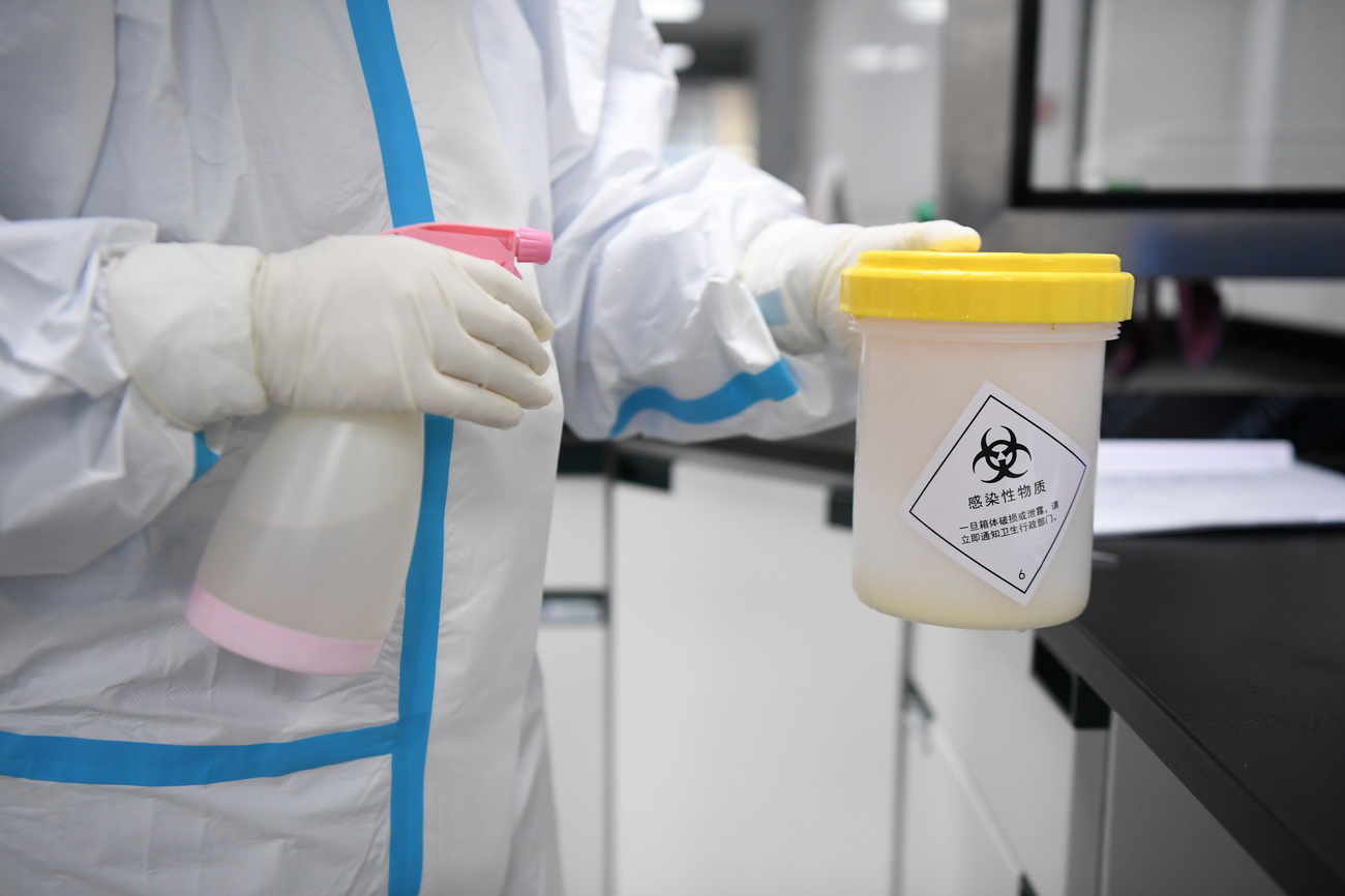 3月10日，长沙卫实医学检测所的工作人员在前处理室为样本容器外部消毒。