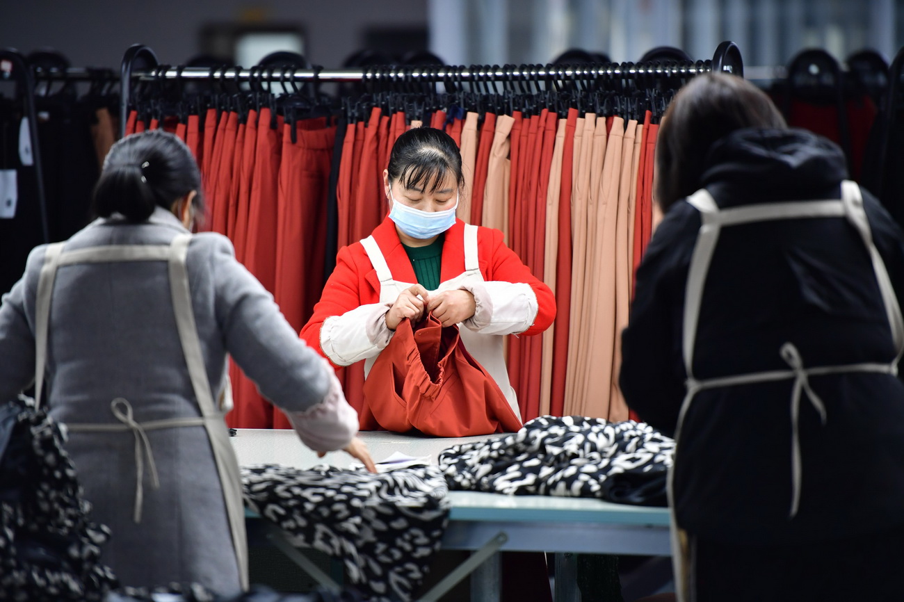 3月11日，在城固縣博望街道辦事處江灣社區一服裝廠內，工人在檢查服裝產品。