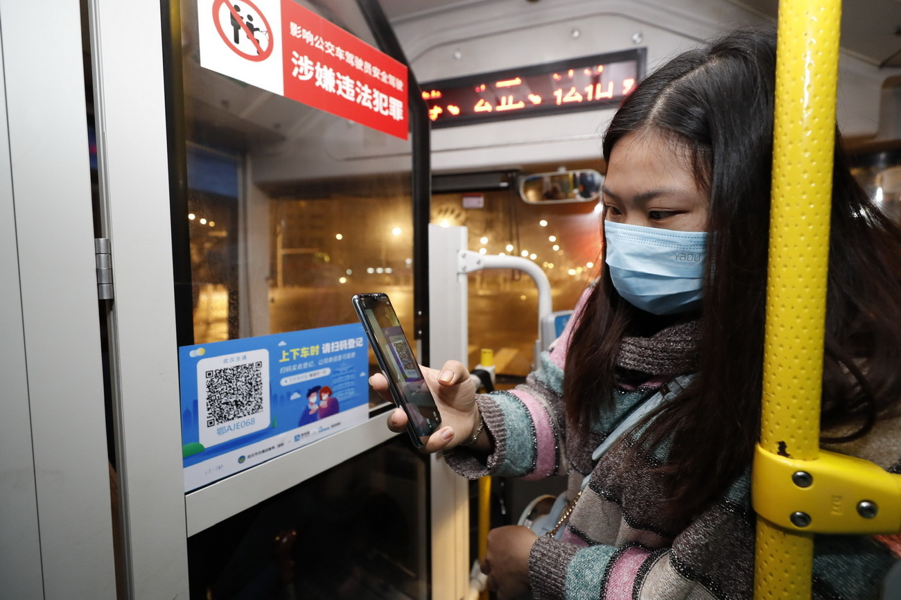 3月25日，在武昌火车站综合体站始发的首趟518路公交车上，乘客用手机支付宝APP扫码实名登记，显示健康绿码后方可乘车。