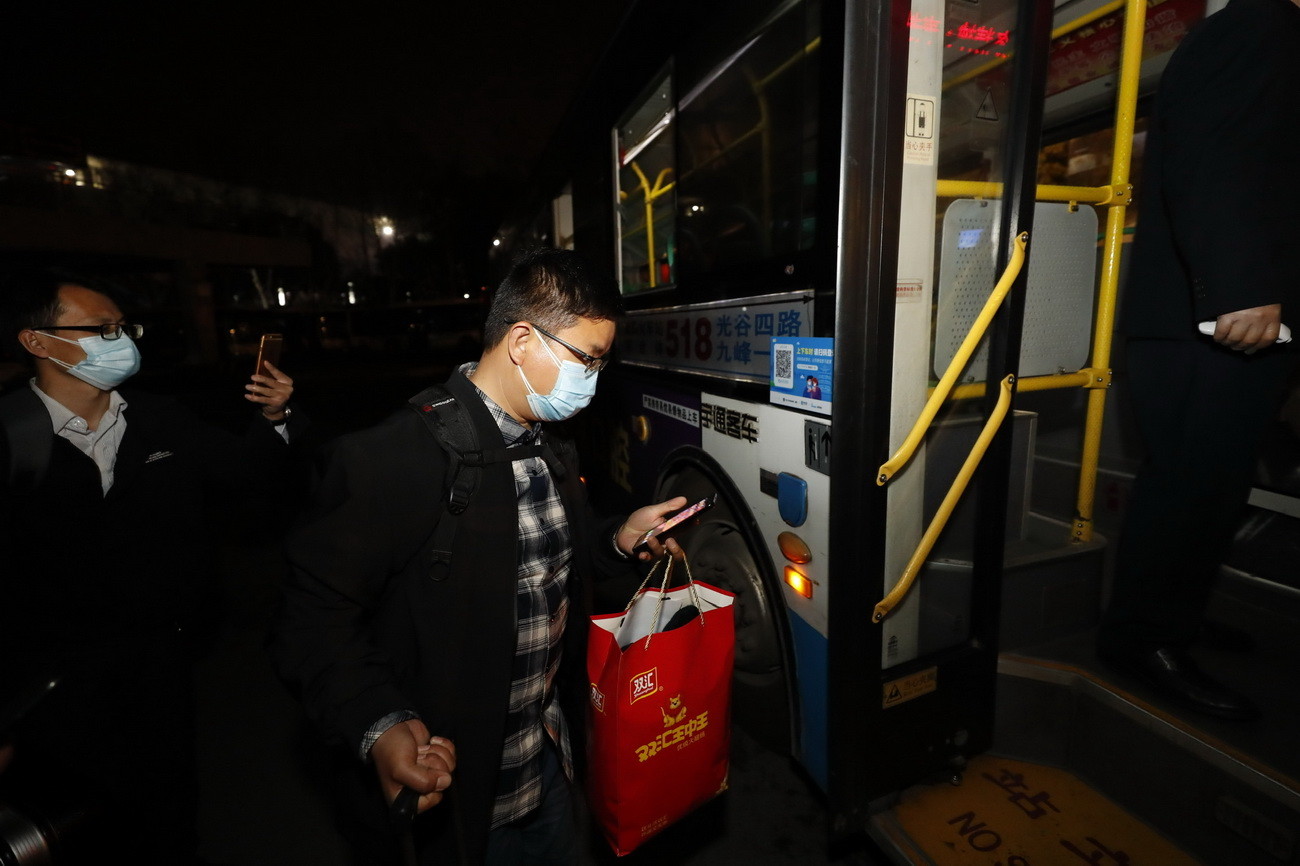 3月25日，在武昌火车站综合体站始发的首趟518路公交车上，乘客用手机扫码实名登记后上车。