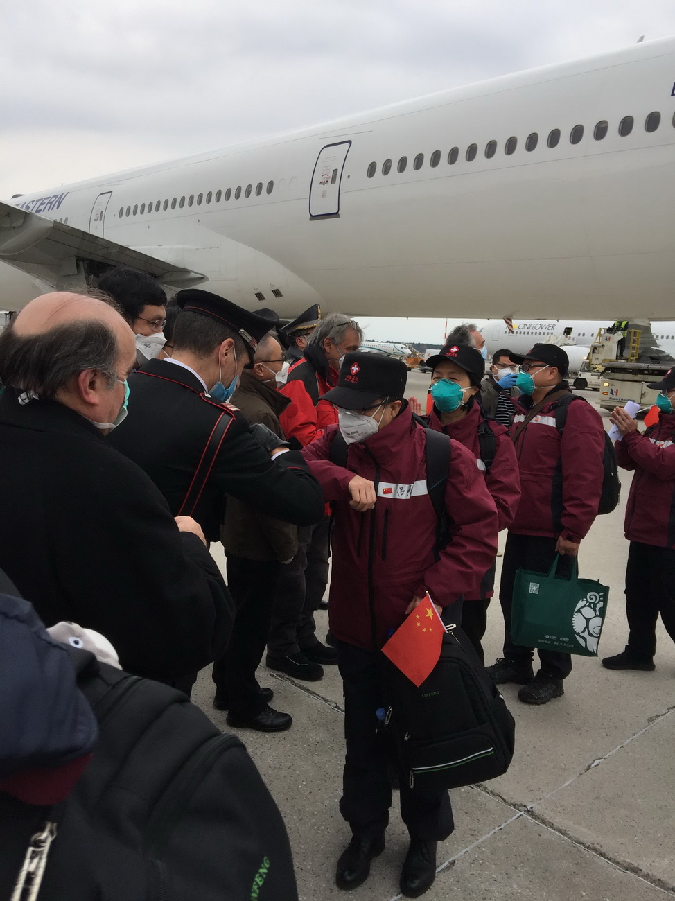 3月25日，在意大利米蘭馬爾奔薩機場，意方人員以“擊肘”的方式歡迎中國第三批赴意大利抗疫醫療專家組成員的到來。