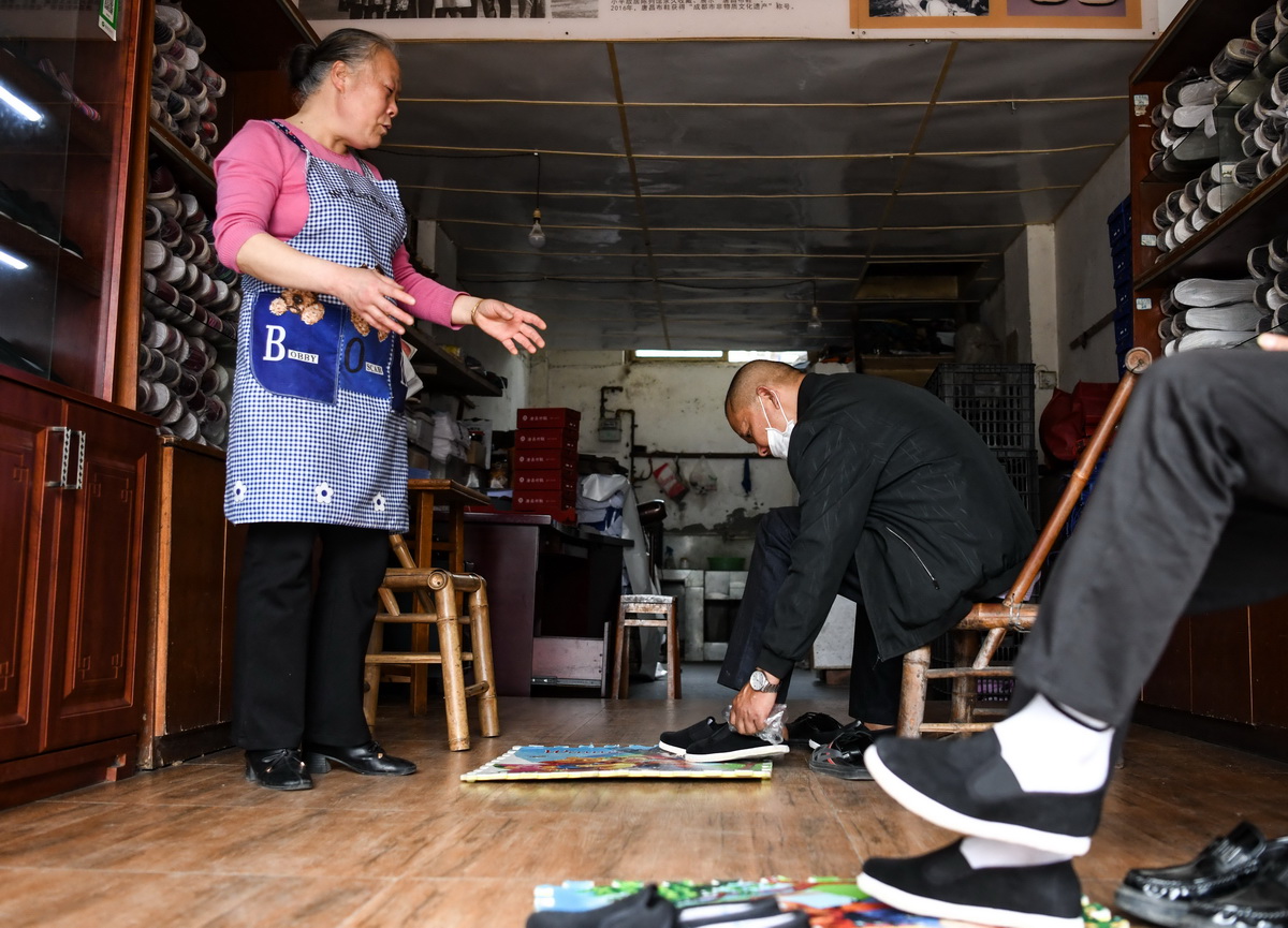 4月16日，在唐昌鎮，賴淑芳（左）為店裡的顧客試鞋。