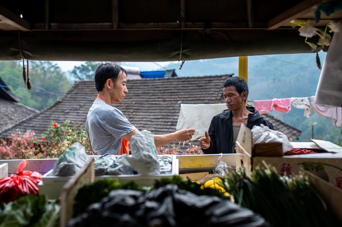 4月12日，在雲南省勐海縣布朗山鄉曼囡村曼班三隊，一名村民（右）在購買蔬菜。