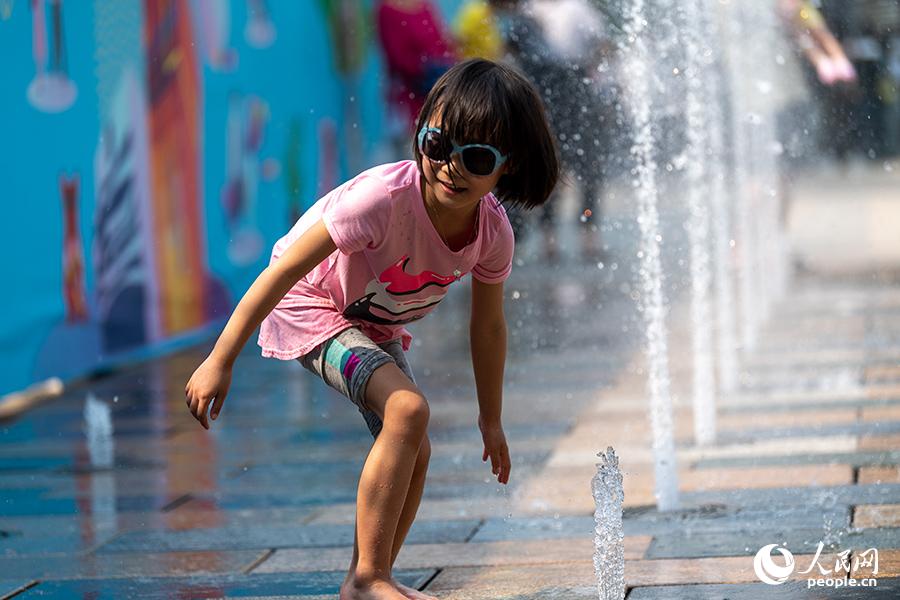 5月1日，在北京三裡屯，孩子在噴水池戲水降溫。（人民網記者 翁奇羽 攝）