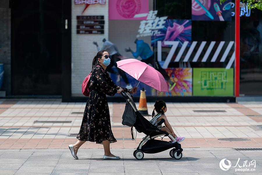 5月1日，在王府井步行街，路人使用遮陽傘遮擋烈日。（人民網記者 翁奇羽 攝）