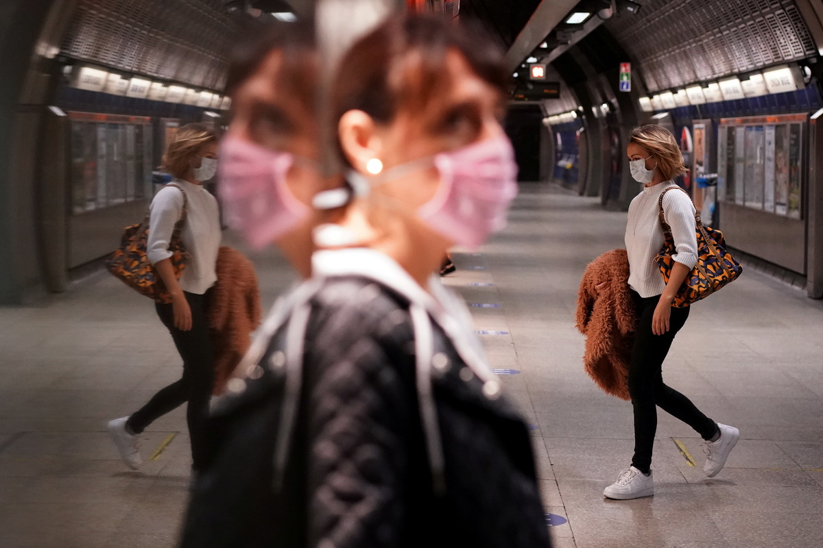 5月14日，在英国伦敦的一座地铁站，人们戴着口罩出行。