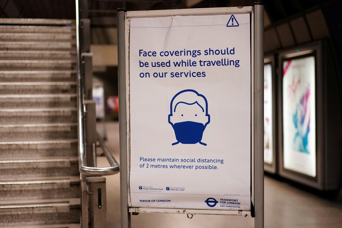 这是5月14日在英国伦敦一座地铁站内拍摄的提醒人们戴口罩出行并保持社交安全距离的告示牌。