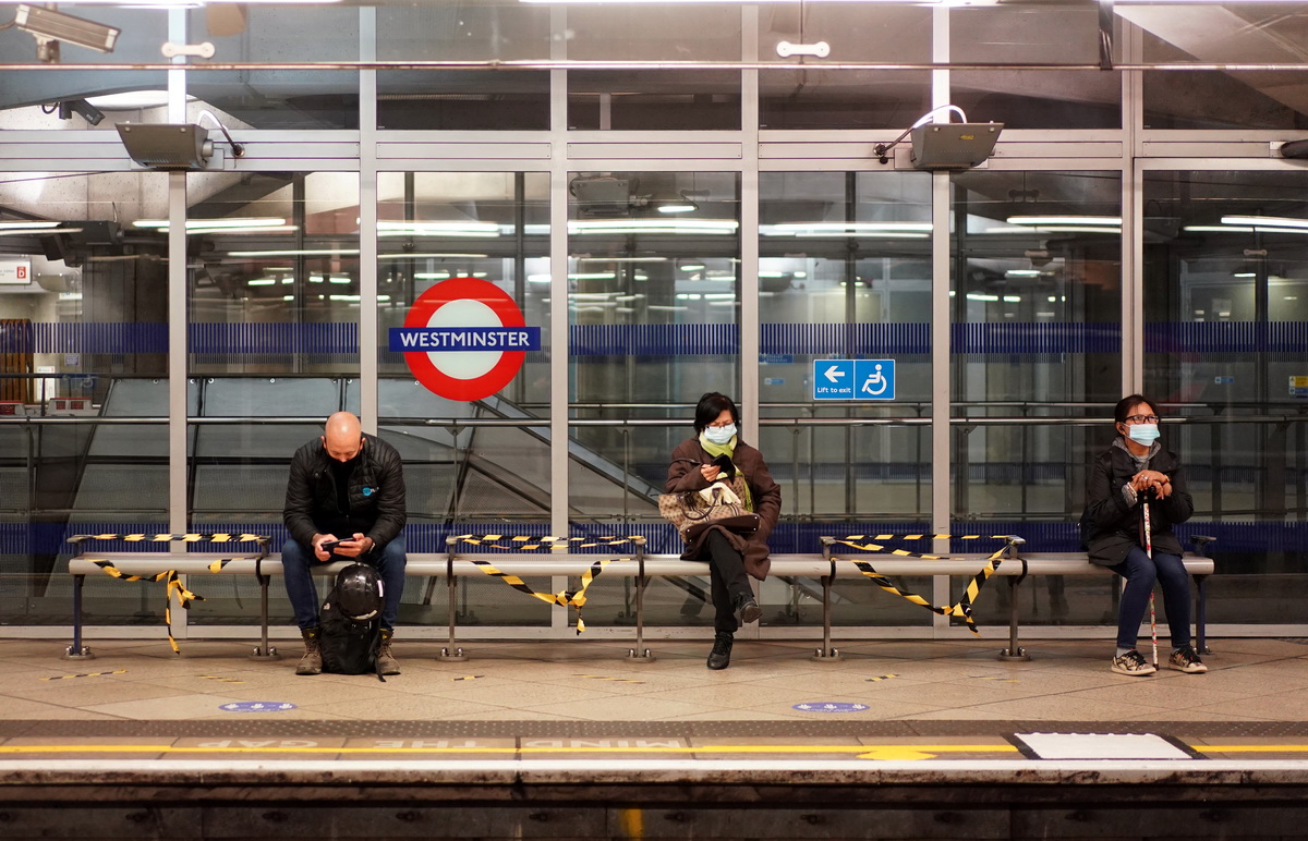 5月14日，在英国伦敦的一座地铁站，人们戴着口罩等候列车。