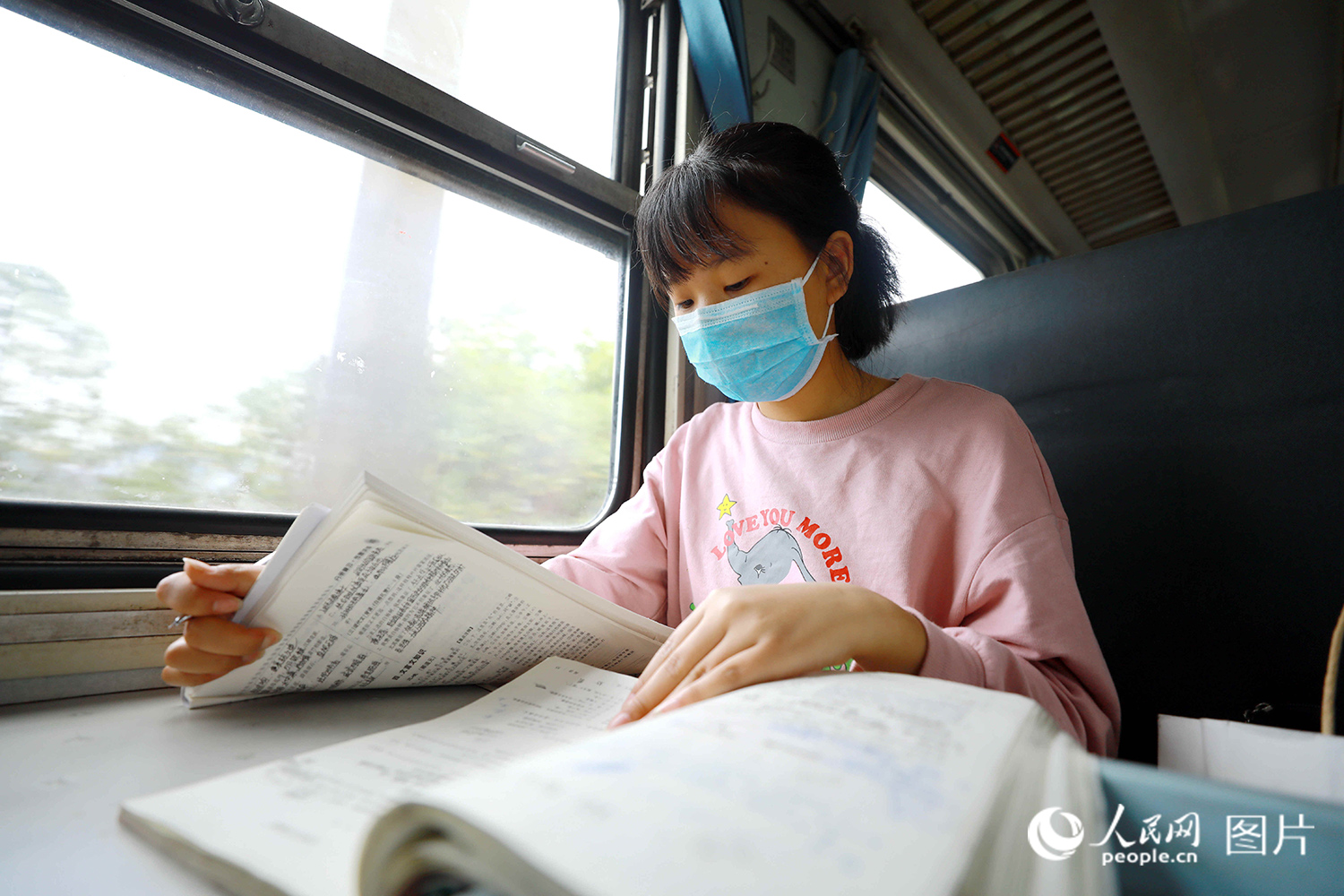 5633次列車上，一名彝族學生正在翻閱學習資料。（李鍇 攝）