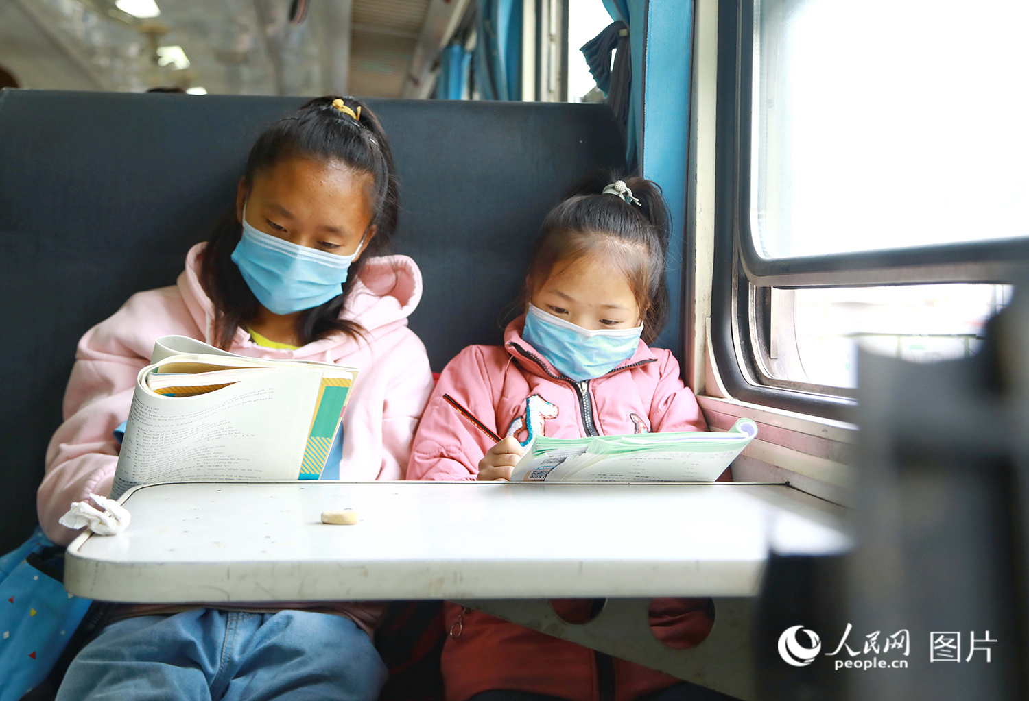 5633次列車上，兩名彝族學生正在寫作業。（李鍇 攝）