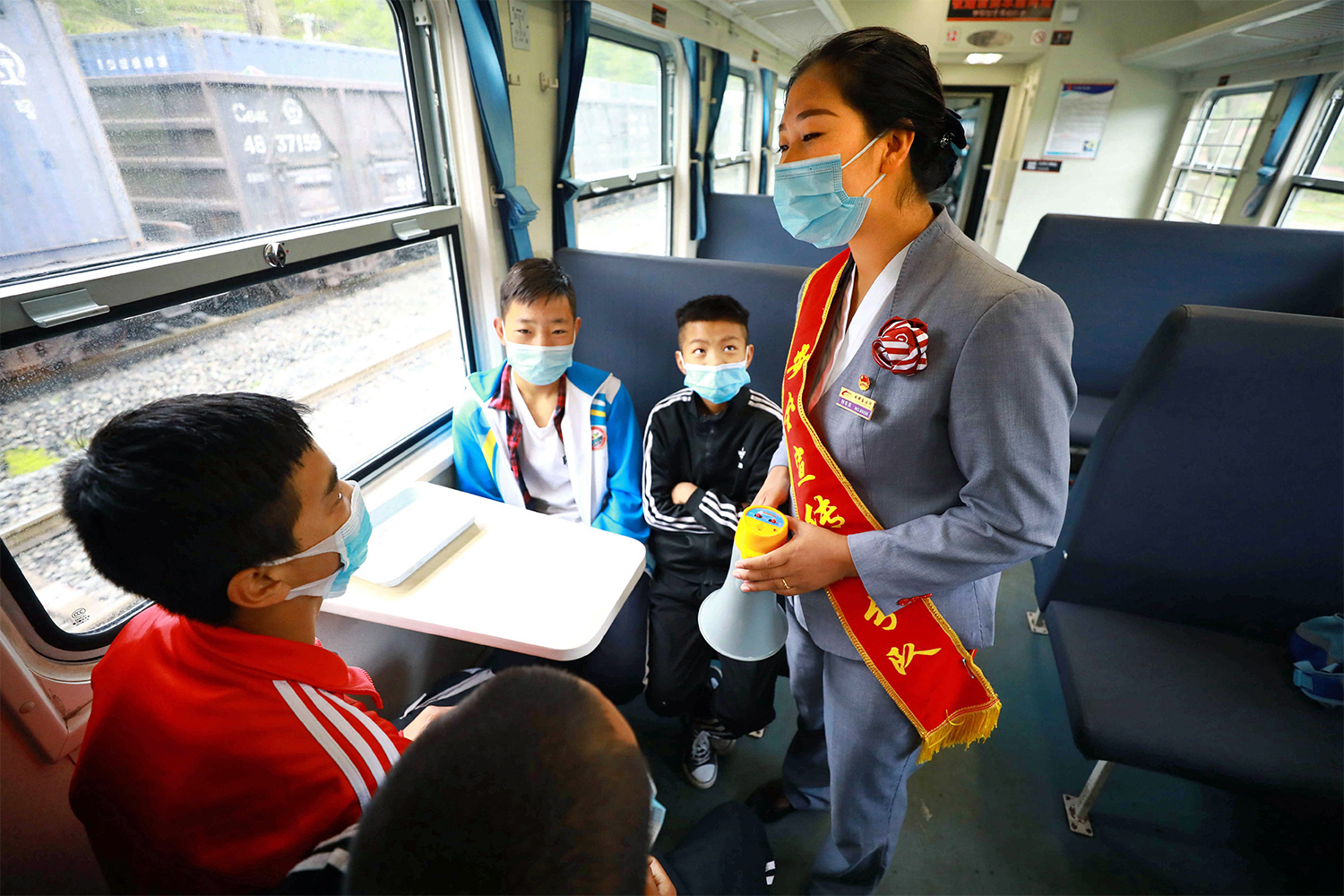 5633次列車彝族乘務員瓦扎阿基莫為彝族學生宣傳疫情防護知識。（李鍇 攝）