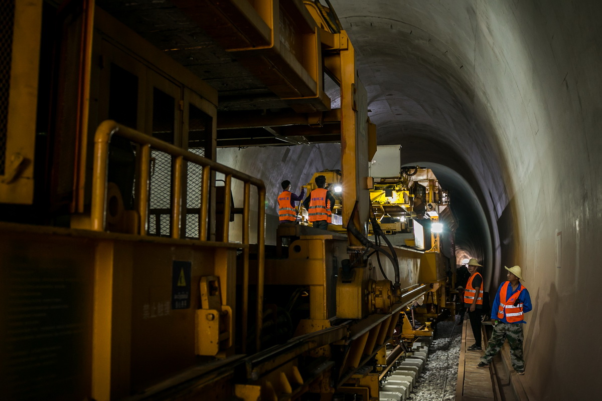 5月23日，在老撾萬象省庚凱村隧道的中老鐵路施工現場，中老兩國工人協力鋪軌。