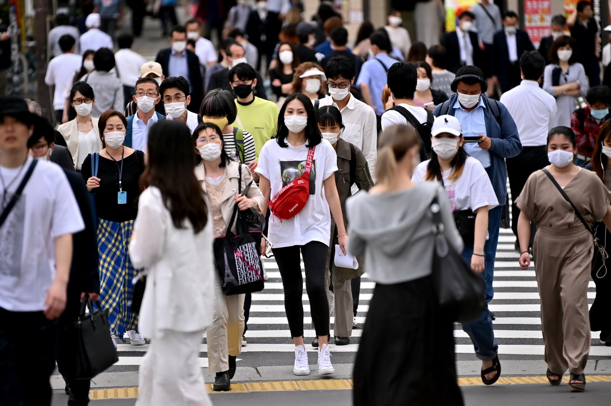 5月25日，在日本東京，戴口罩的行人穿過馬路。