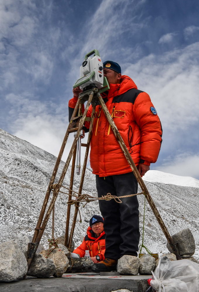 自然資源部第一大地測量隊隊員鄭林（站立者）和武光偉在對珠峰峰頂進行交會觀測（5月27日攝）。