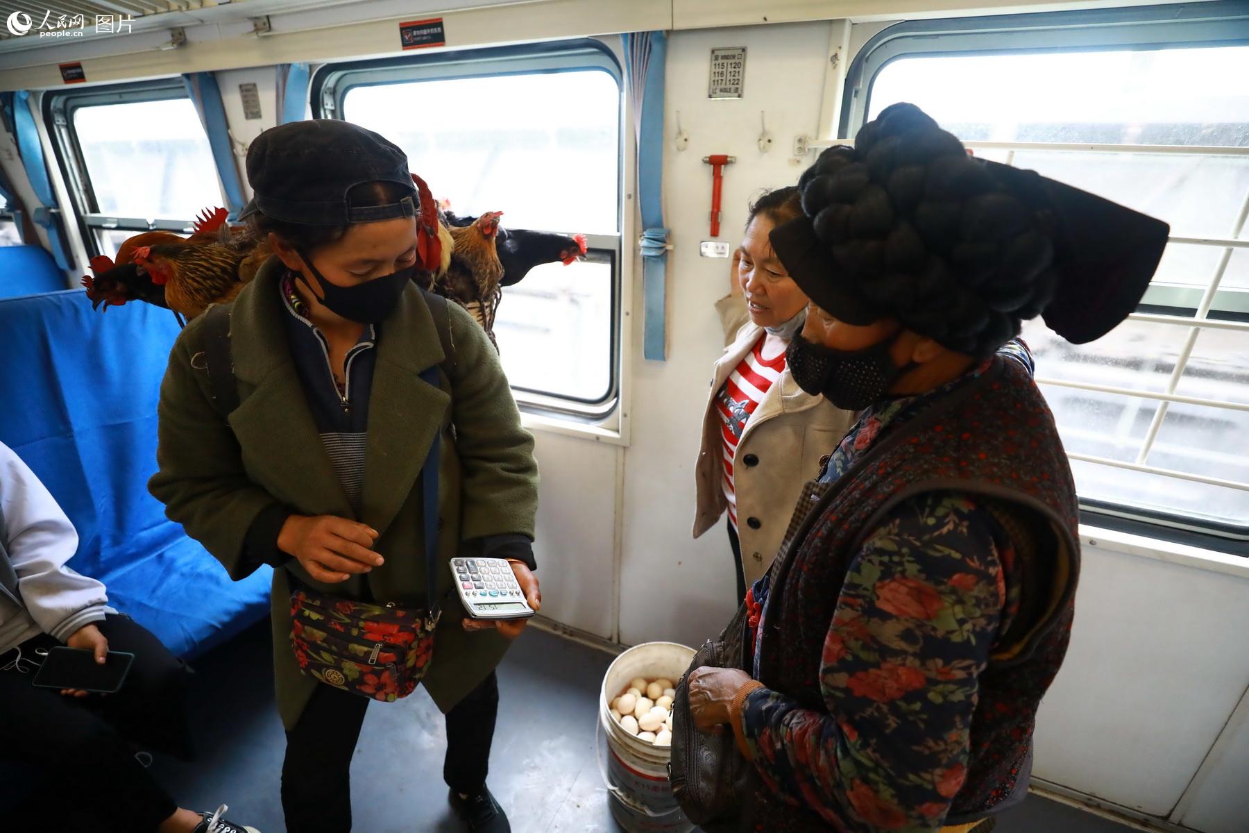 5月17日，5633次列車上，三名乘車趕集的彝族旅客正在進行交談。（李鍇 攝）