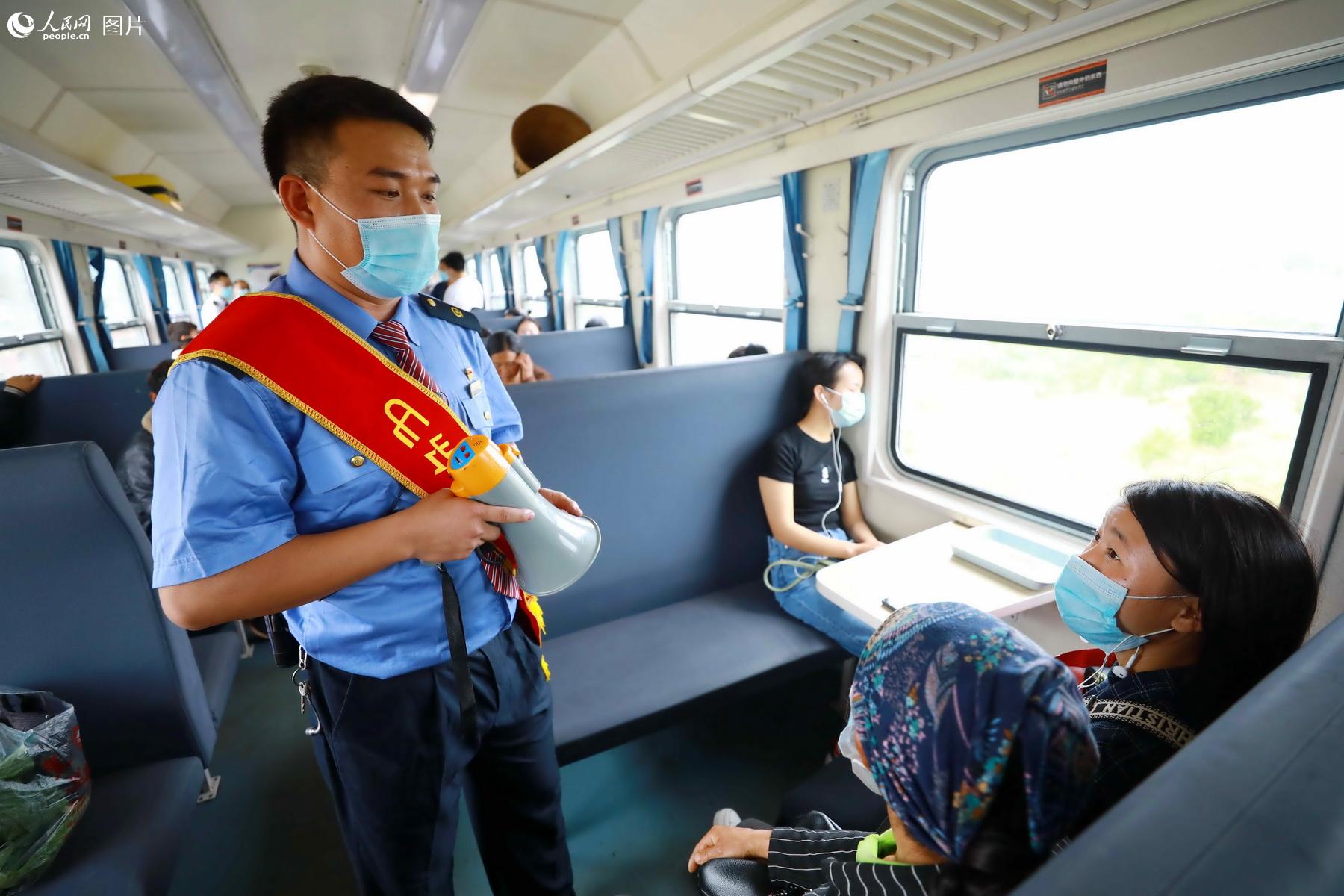 5月21日，5633次列車彝族乘務員俄木日古向彝族旅客宣傳安全乘車注意事項。（李鍇 攝）