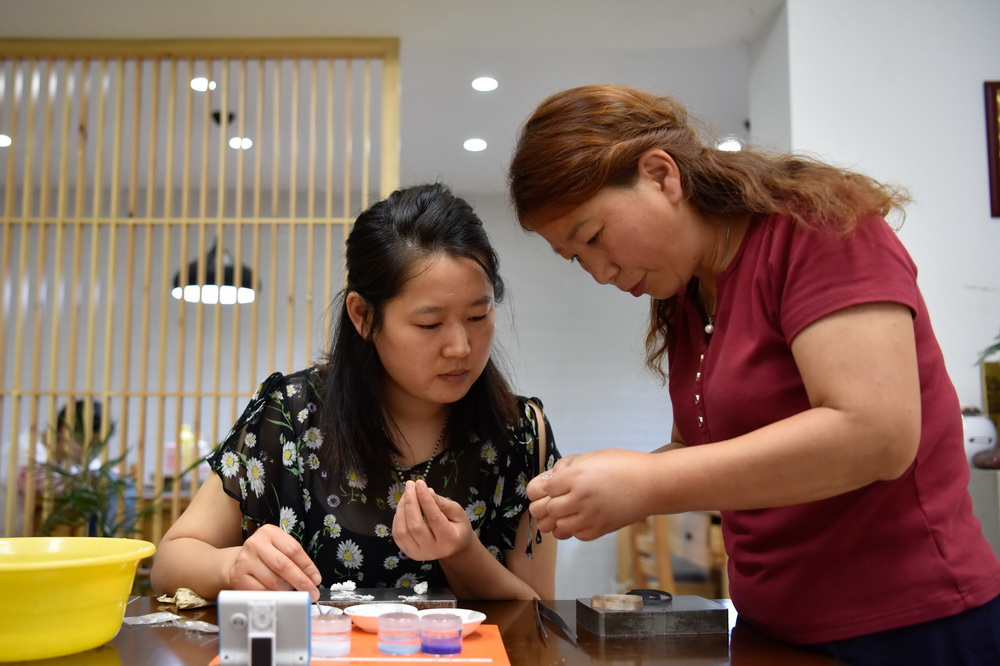 6月10日，在道安銀花絲工作室，道安（右）在指導匠人進行琺琅工序，為銀花絲上色。