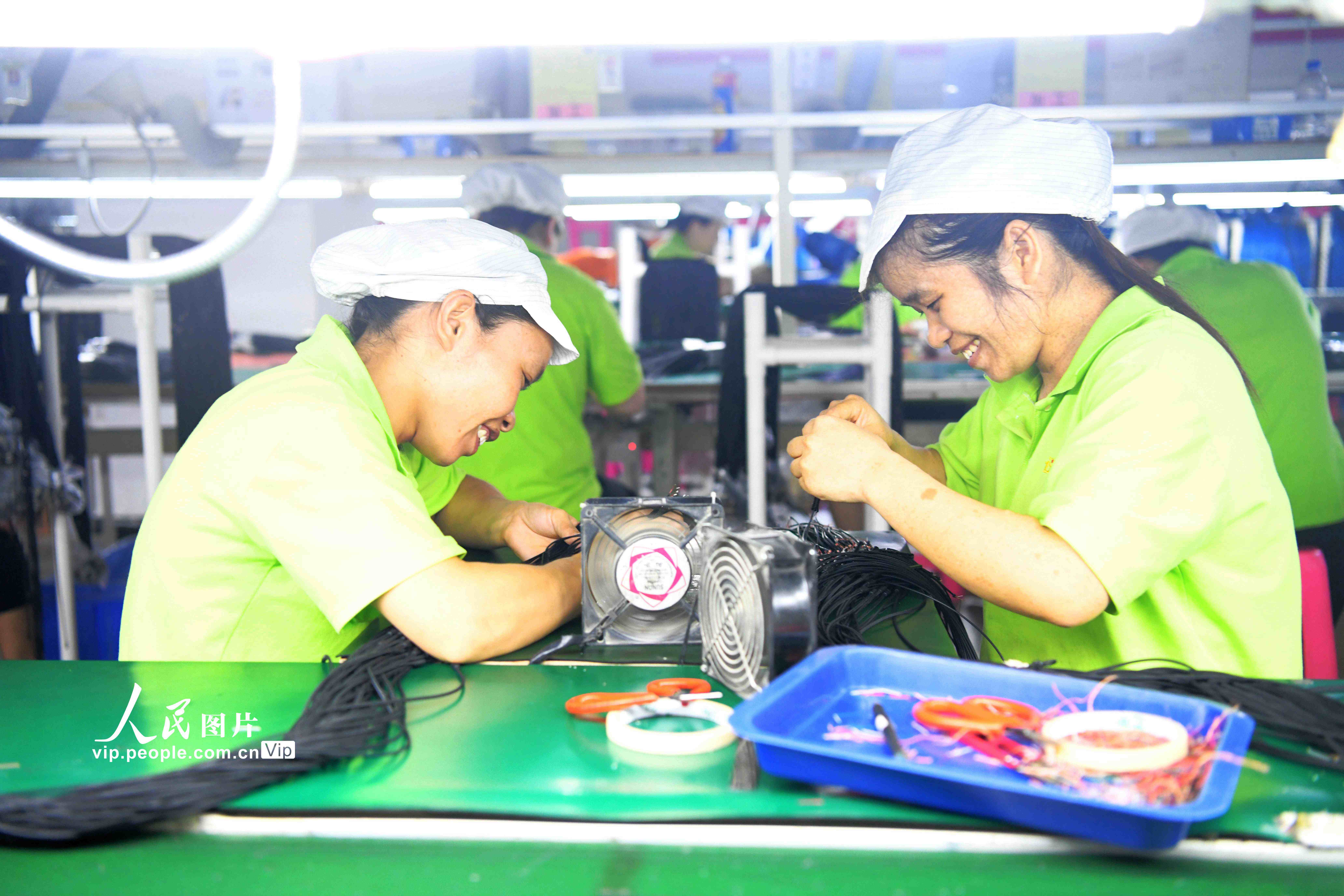 幾位貧困婦女正在“仫佬家園”裡一家電子廠的“巾幗扶貧車間”務工。