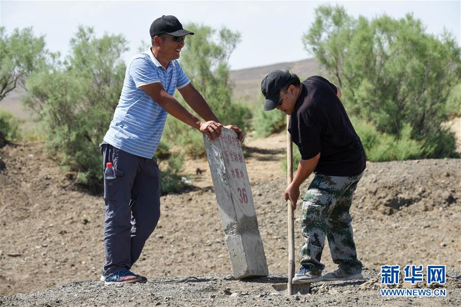 阿达比亚特（左）和同事将野生动物碰倒的水源地碑重新立好（6月3日摄）。新华社记者 丁磊 摄