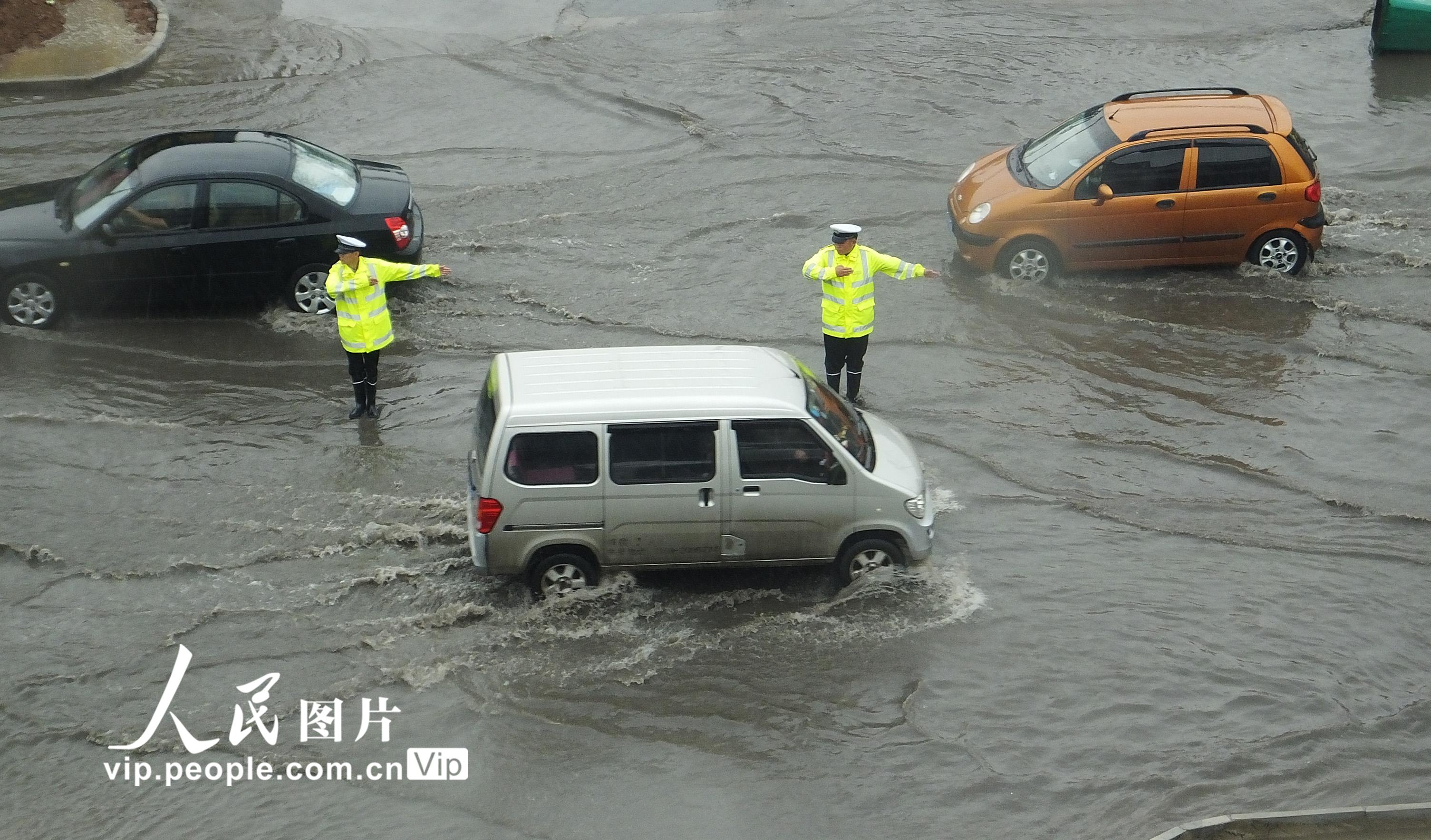 6月16日，山西运城市新绛县交警大队汾河湾中队辅警在108国道汾河湾积水处冒雨指挥交通。 